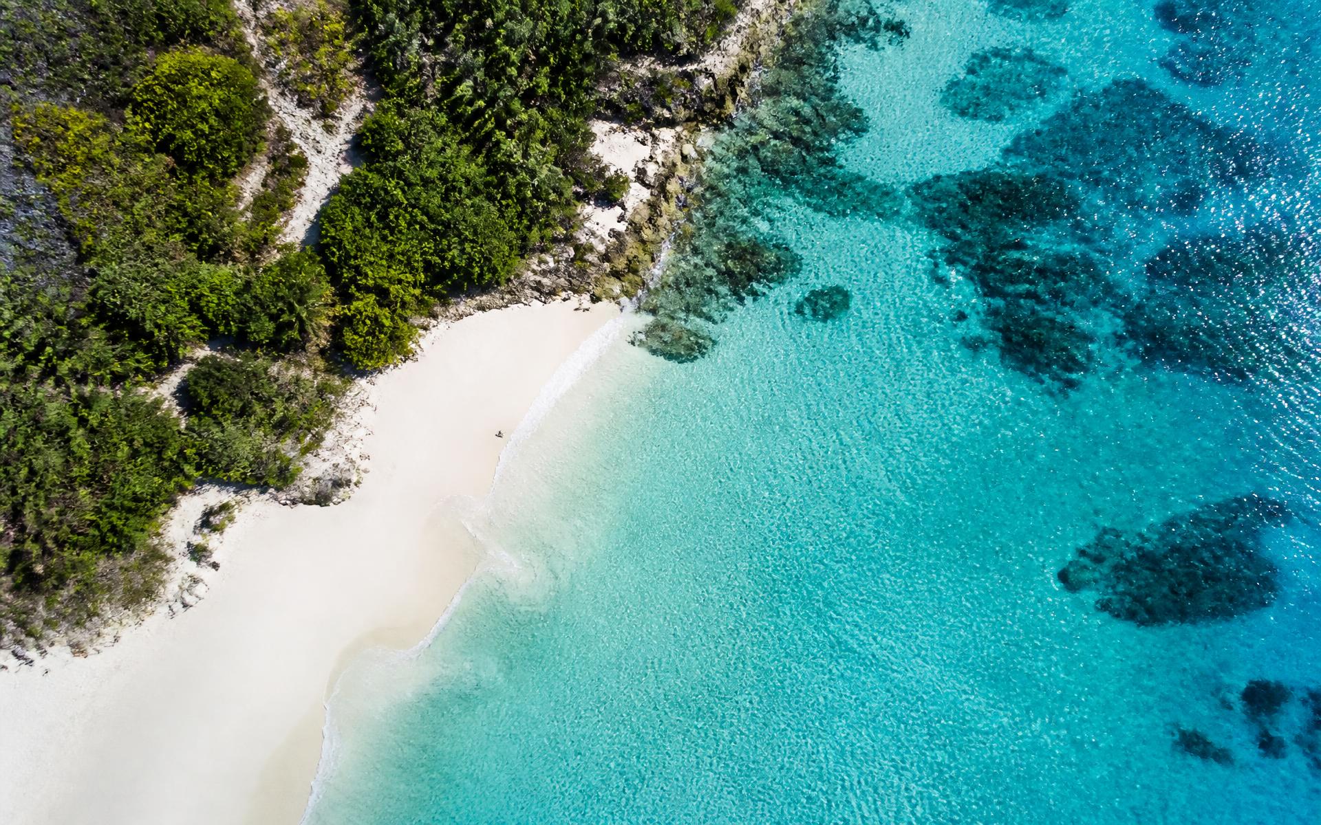 Aerial view of a turquoise coastline with white sand beach